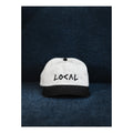 White cap with 'LOCAL' text on a dark textured background