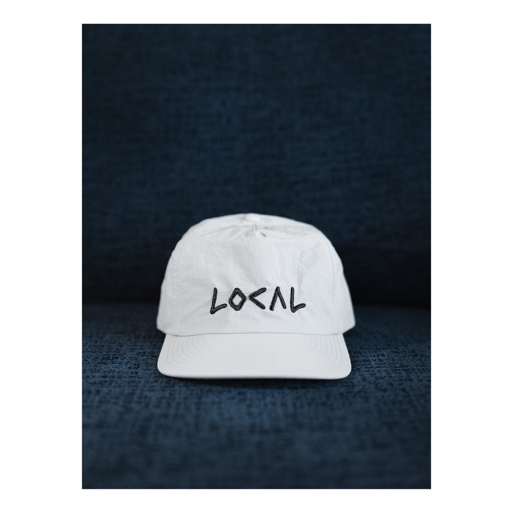 White cap with 'LOCAL' text on a dark textured background