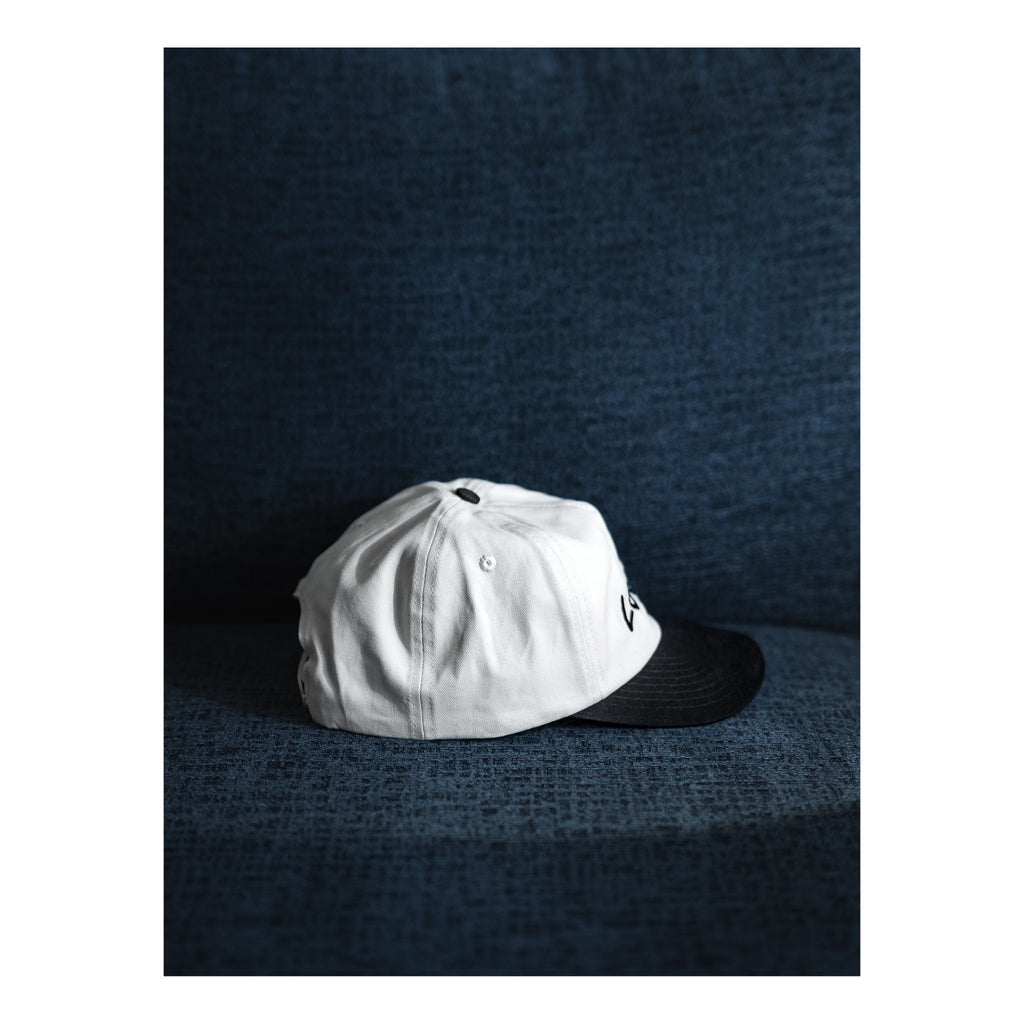 White cap with black brim on a textured dark blue surface