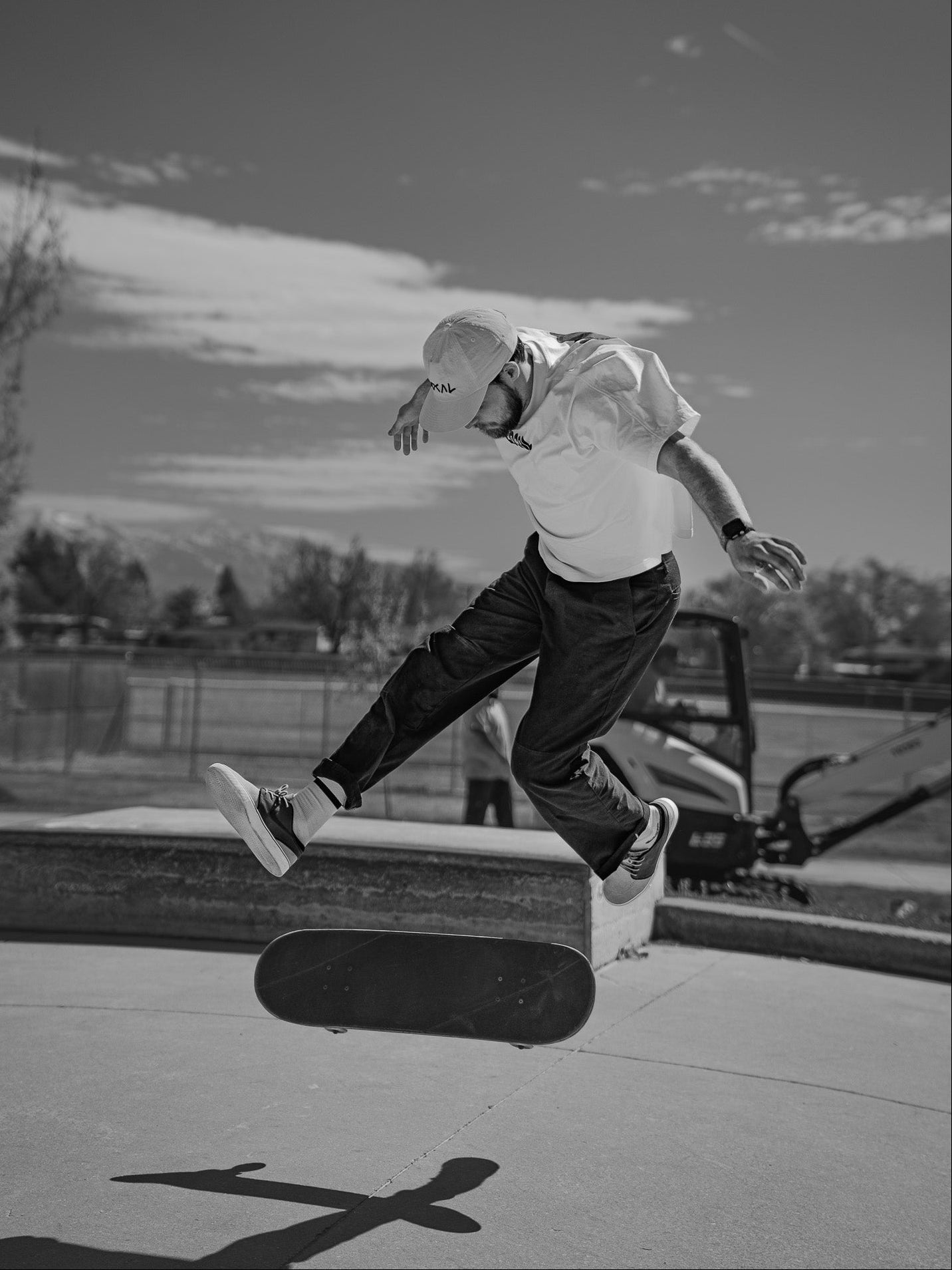 Skateboarder performing a trick at a skate park with a cloudy sky in the background.